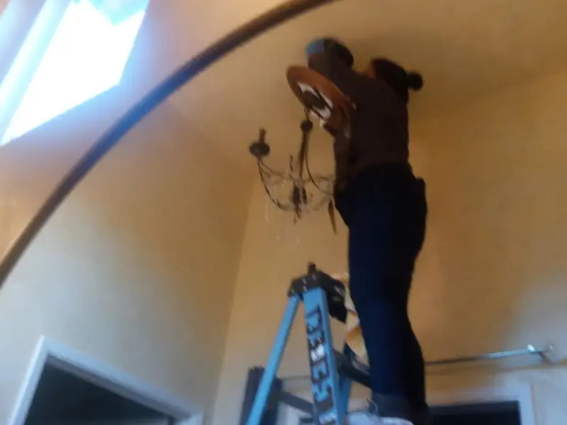 Electrician installing a chandelier in a Neosho residence